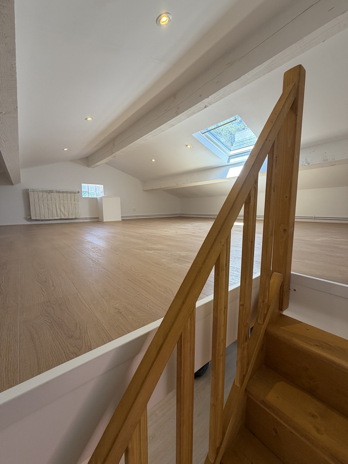 Mezzanine rénovée avec escalier en bois et fenêtre de toit
